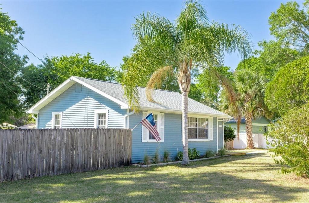 A blue, single-story house with a wooden fence and a palm tree in the yard — 12706 FOREST STREET, TAMPA, FL