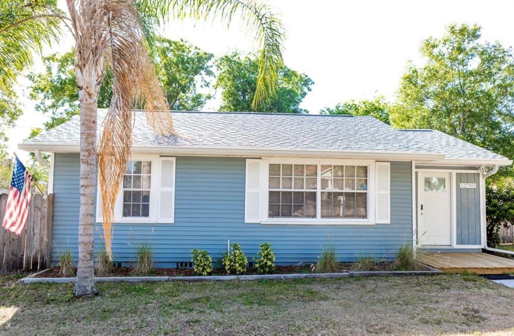 A single-story blue house with white shutters, a front deck, and an American flag — 12706 FOREST STREET, TAMPA, FL