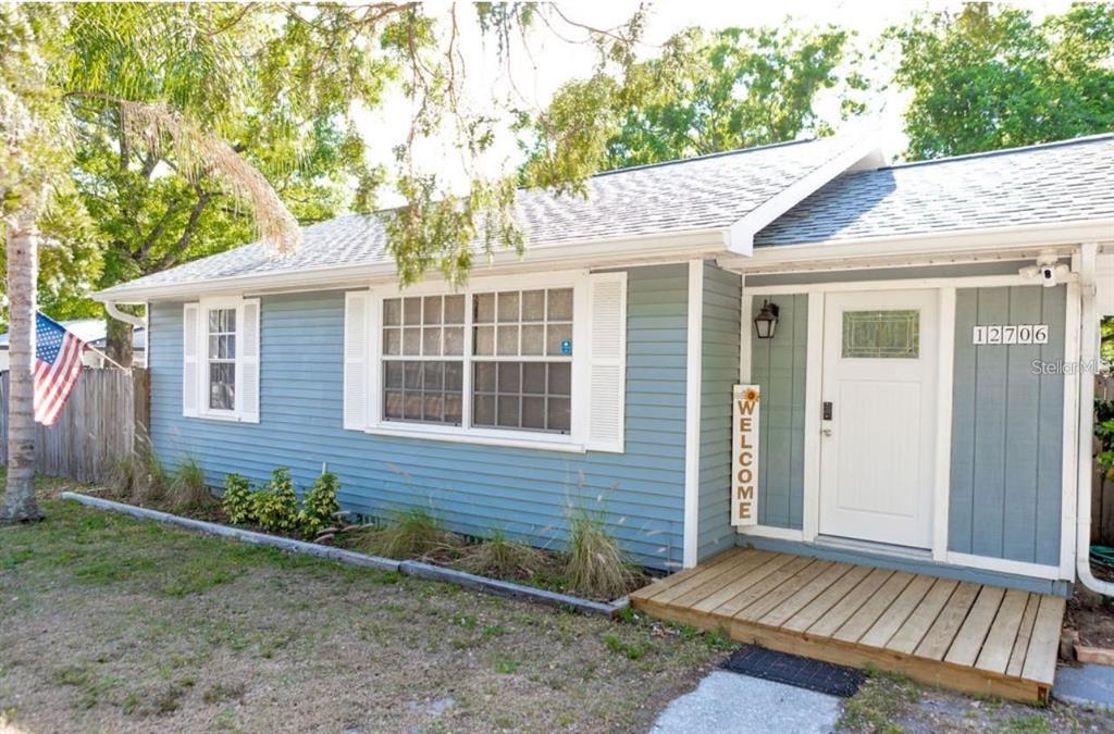 A single-story house with blue siding, a wooden front porch, and a white front door — 12706 FOREST STREET, TAMPA, FL
