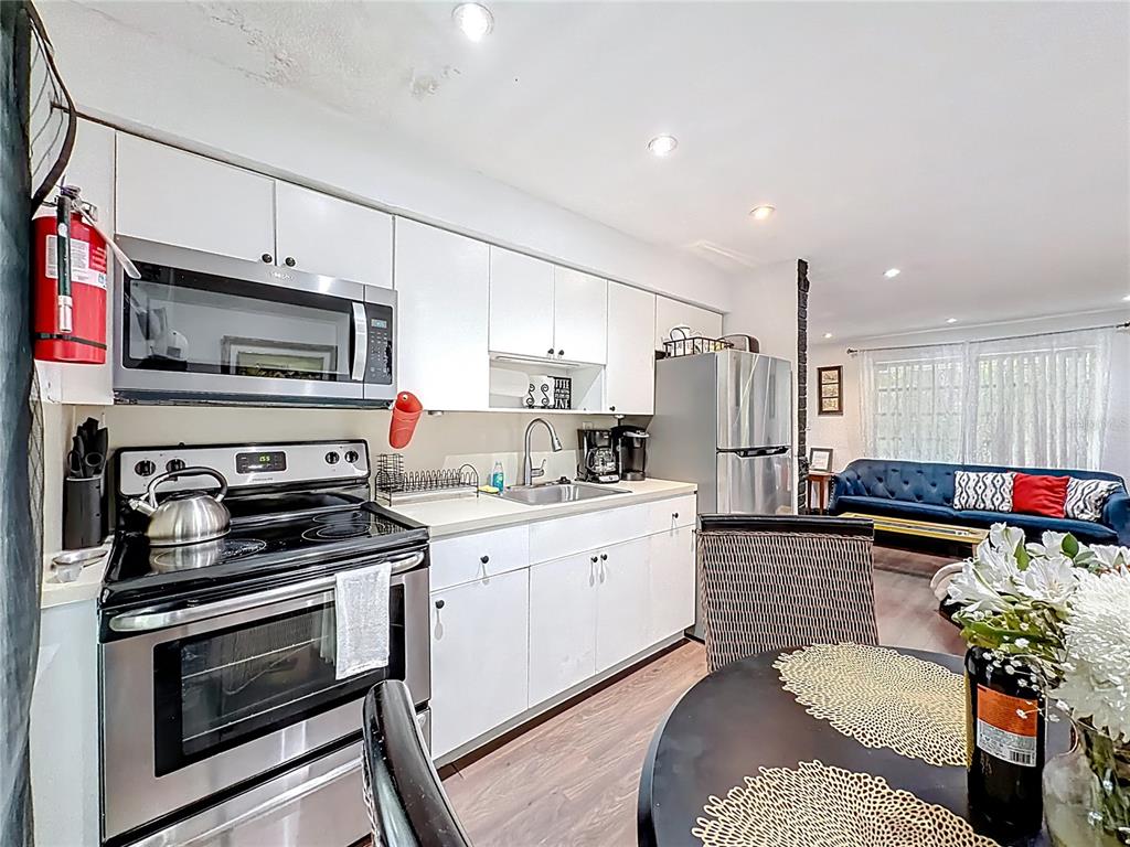 A kitchen with white cabinets and stainless steel appliances opens into a living area — 200 SW 9TH AVENUE UNIT 1-2, FORT LAUDERDALE, FL