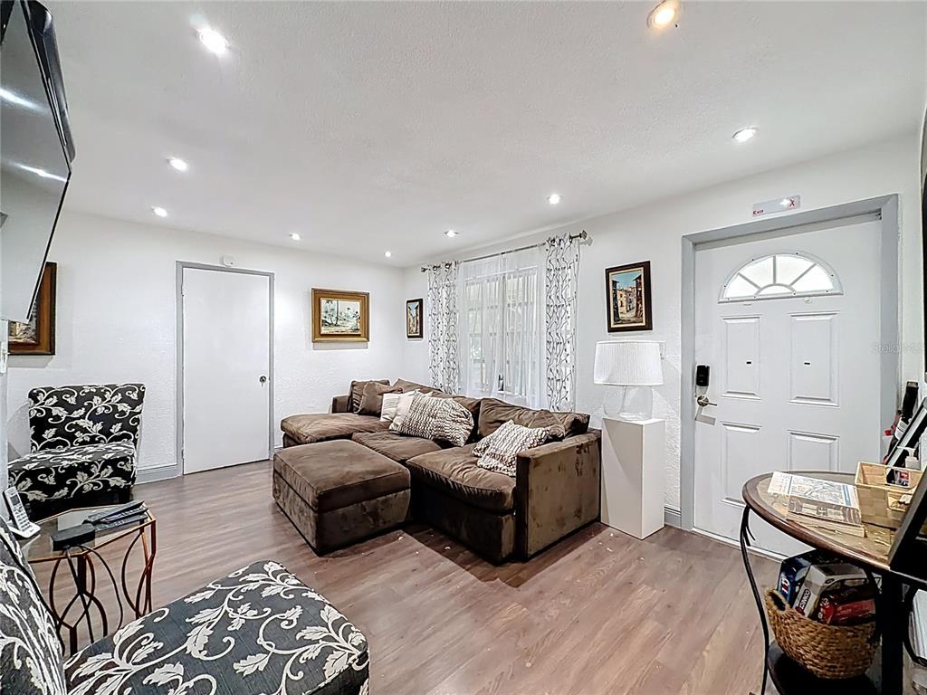 A living room features a brown sectional sofa, patterned accent chairs, and wood-look flooring — 200 SW 9TH AVENUE UNIT 1-2, FORT LAUDERDALE, FL
