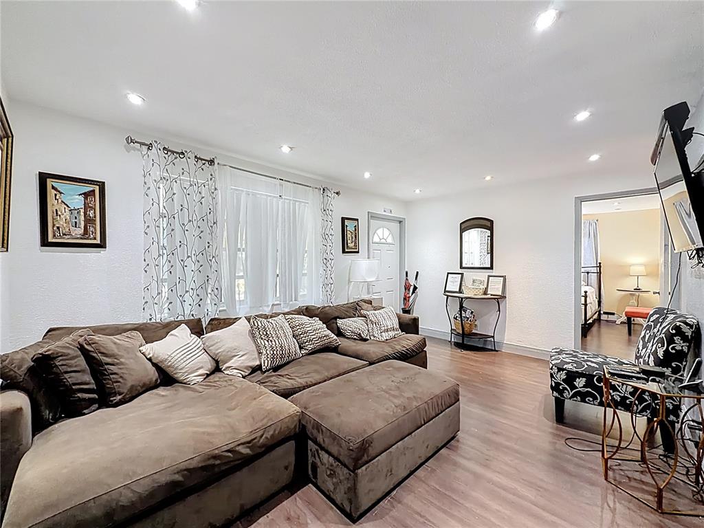 A living room features a large brown sectional sofa, wood-look flooring, and a doorway — 200 SW 9TH AVENUE UNIT 1-2, FORT LAUDERDALE, FL