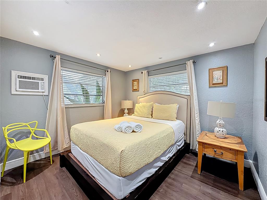 A bedroom features a bed with yellow bedding, a yellow chair, and two windows — 200 SW 9TH AVENUE UNIT 1-2, FORT LAUDERDALE, FL