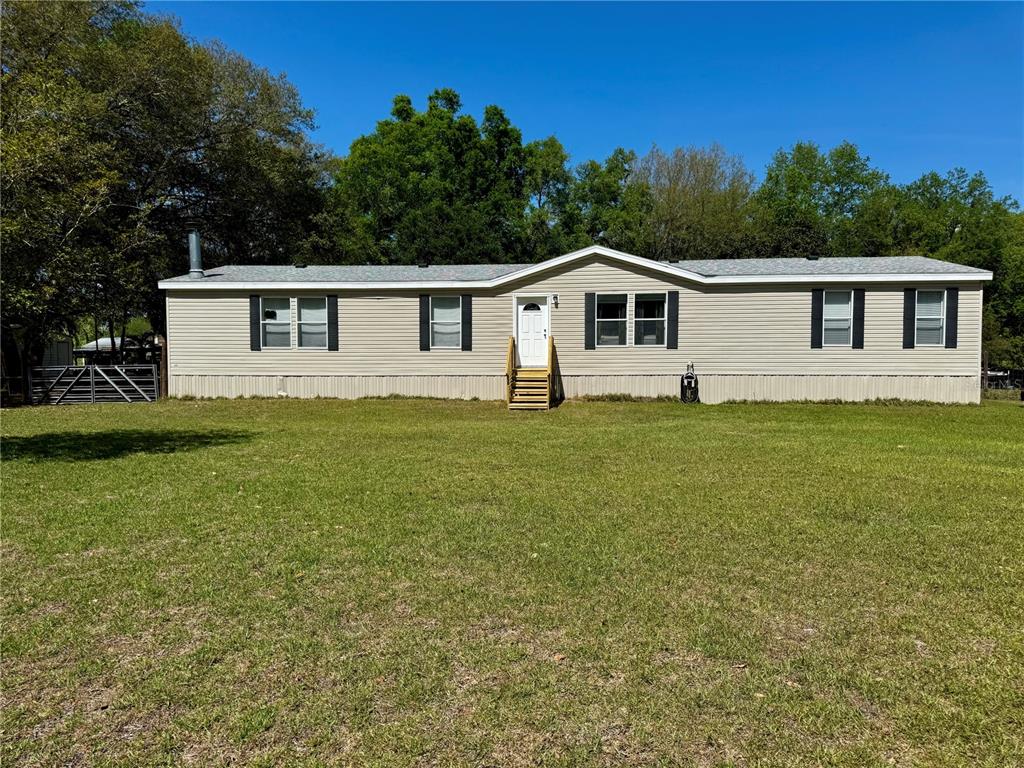 A single-story manufactured home with light siding and a front entrance sits on a lawn — 7222 NW 205TH TERRACE, ALACHUA, FL