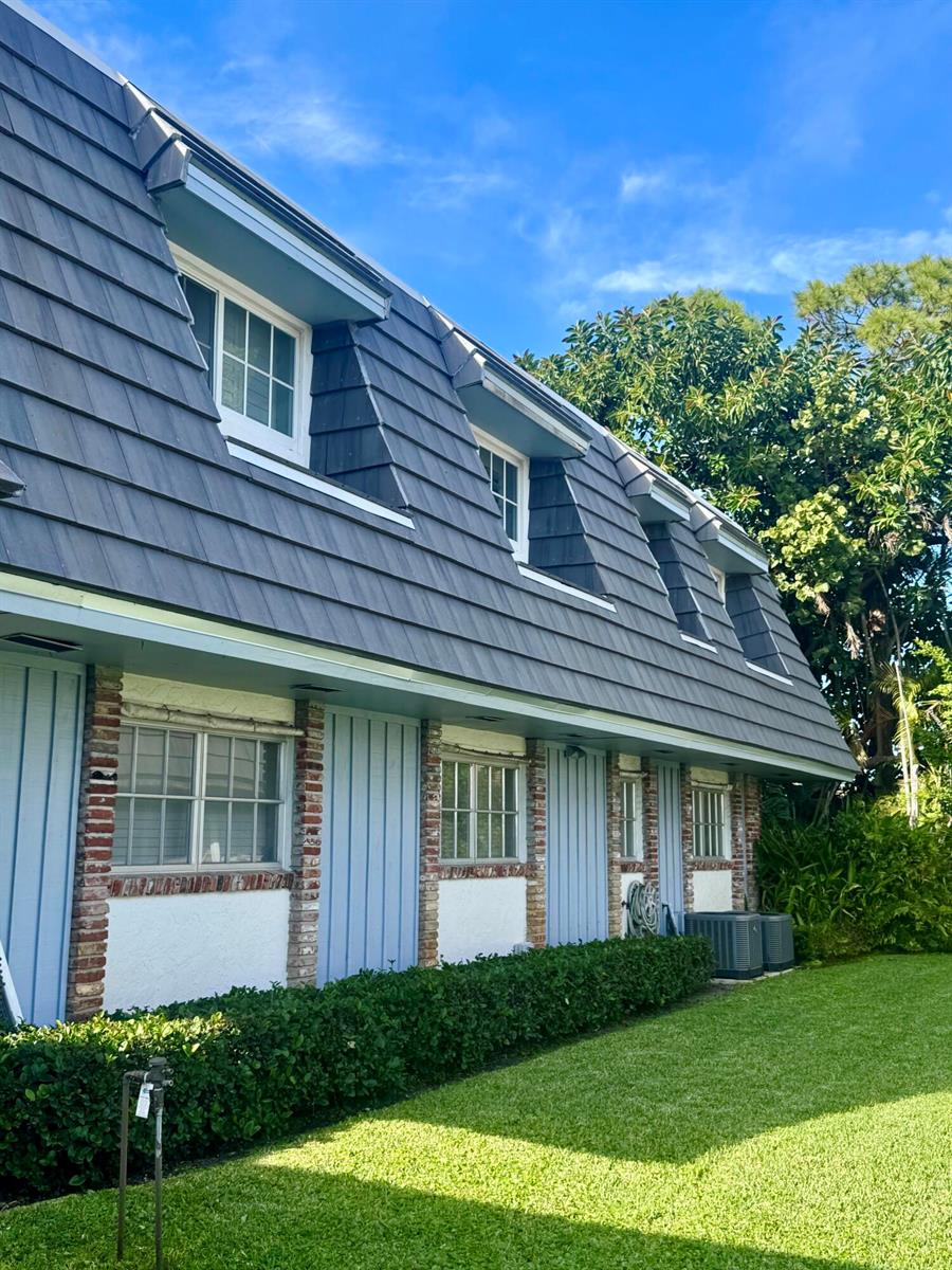 A two-story building exterior with a mansard roof, dormer windows, and blue vertical siding — 419 Pine Tree Court # 19, Atlantis FL 33462, ATLANTIS, FL