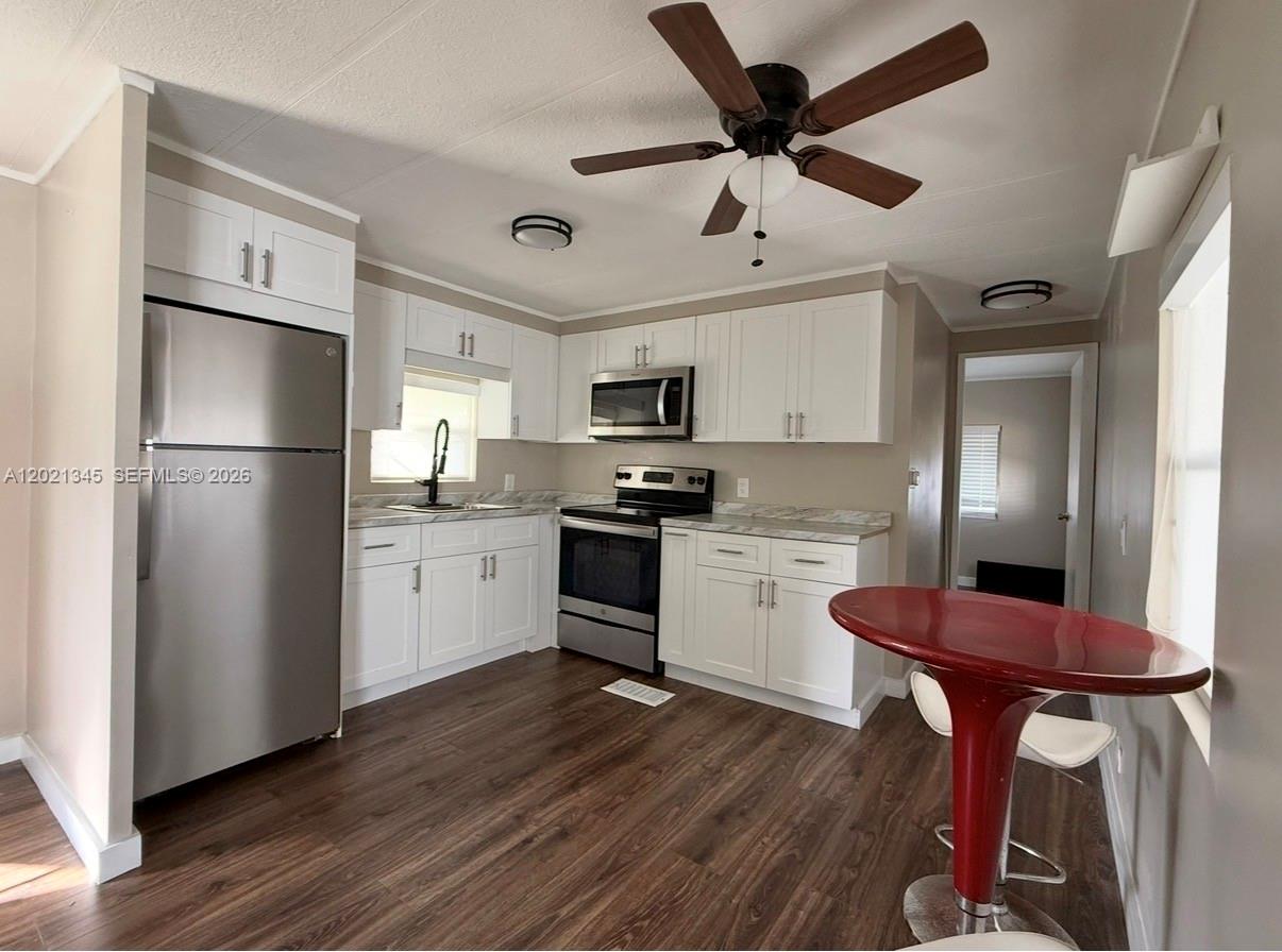 A kitchen features white cabinets, stainless steel appliances, and a red pedestal table — 1332 S 33 AVE, Hollywood FL 33021, HOLLYWOOD, FL