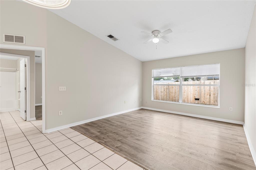A room with light-colored walls, wood-look flooring, a ceiling fan, and a large window — 37210 GRASSY HILL LANE, DADE CITY, FL