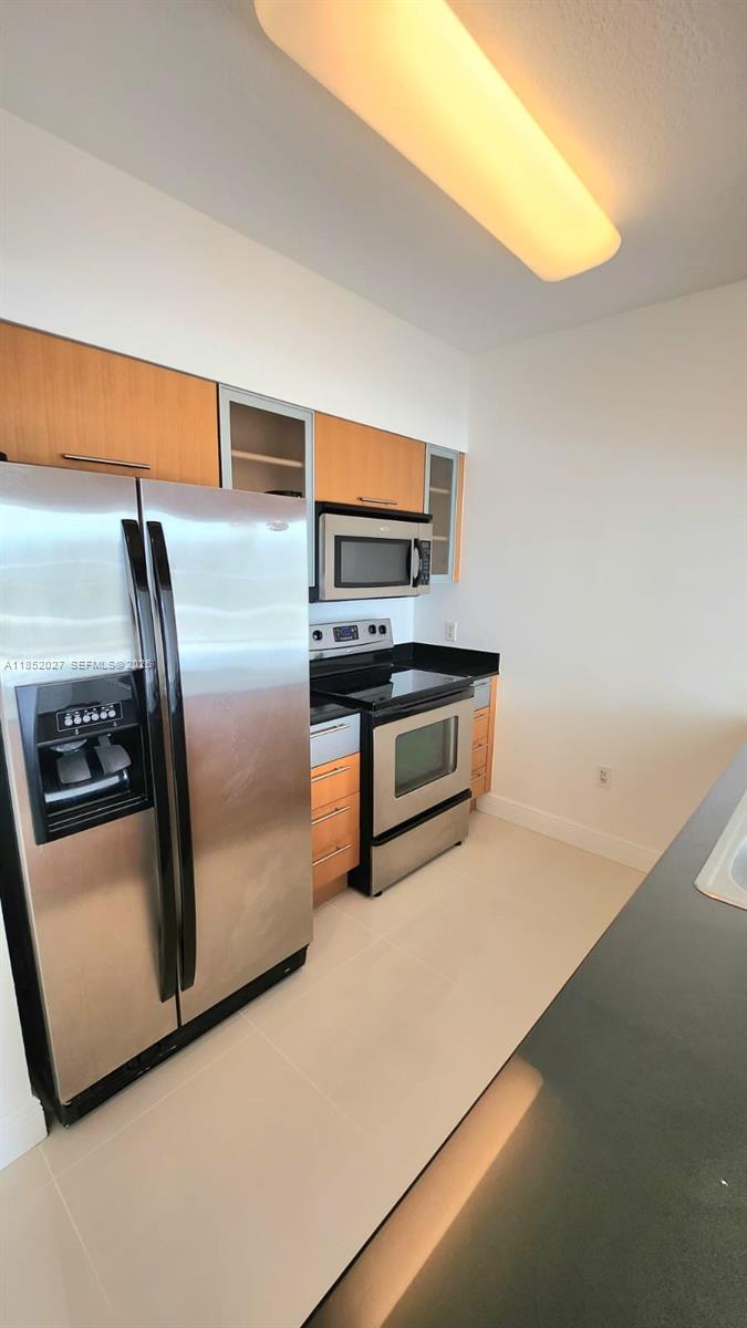 A kitchen features stainless steel appliances, light wood cabinets, and dark countertops — 1750 N Bayshore Dr # 2010, Miami FL 33132, MIAMI, FL
