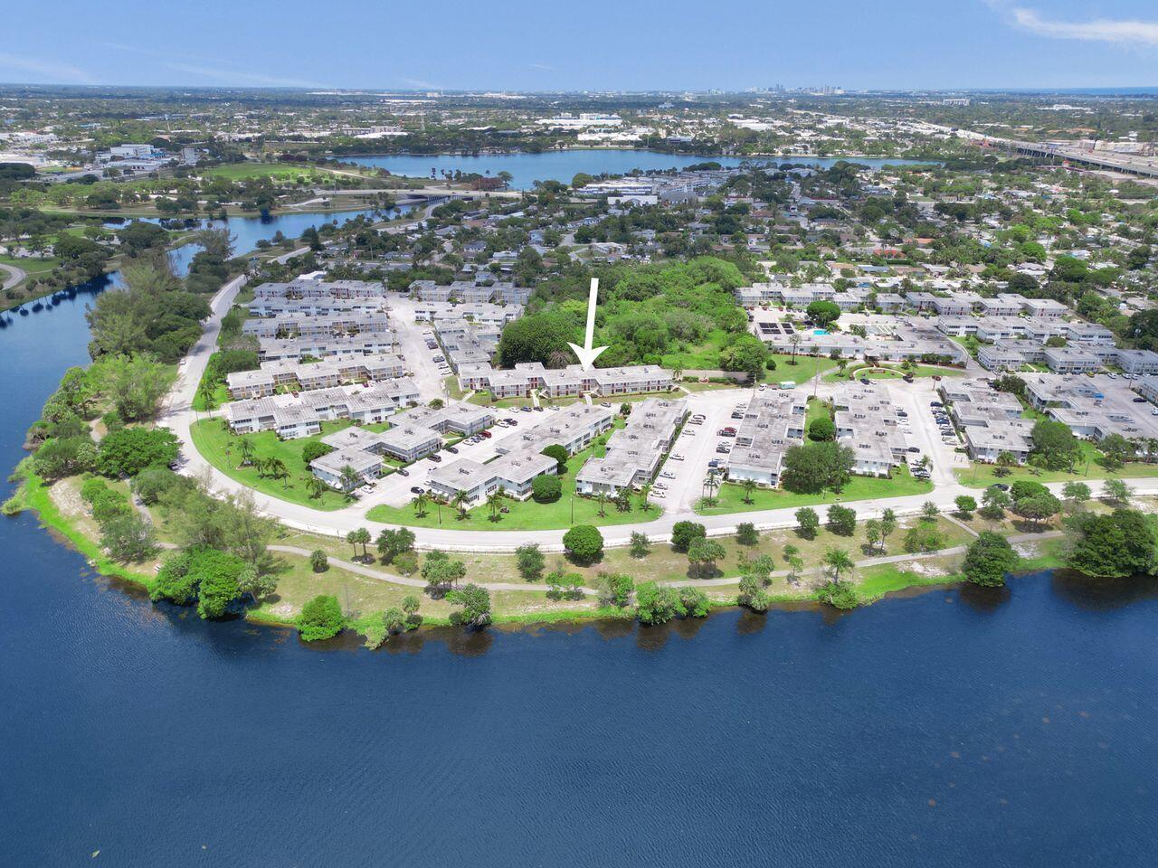 An aerial view of a multi-building apartment complex situated along a large lake — 3120 Cynthia Lane # 207, FL 33461, FL
