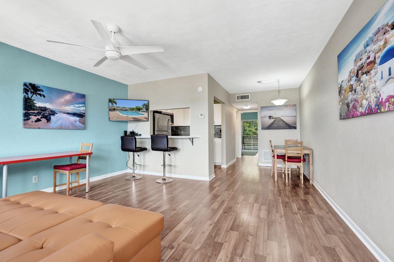 A living and dining area with light wood floors, a blue accent wall, and ceiling fan — 3120 Cynthia Lane # 207, FL 33461, FL