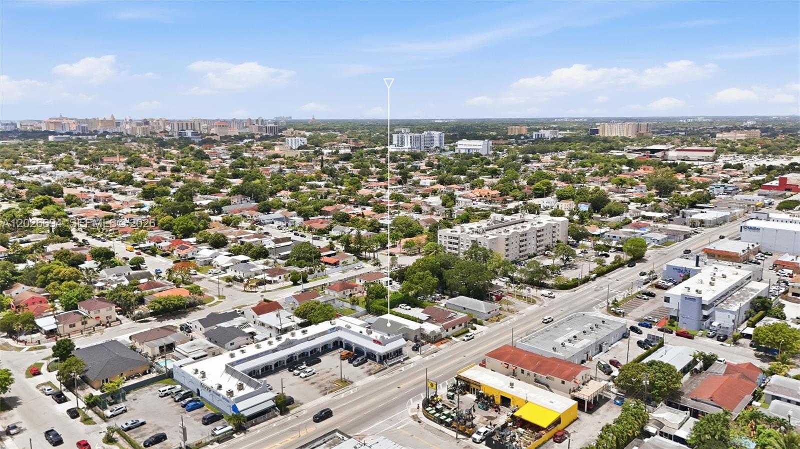 An aerial view shows a commercial strip mall and surrounding residential neighborhood under a blue sky — 3240 NW 7th St, Miami FL 33125, MIAMI, FL