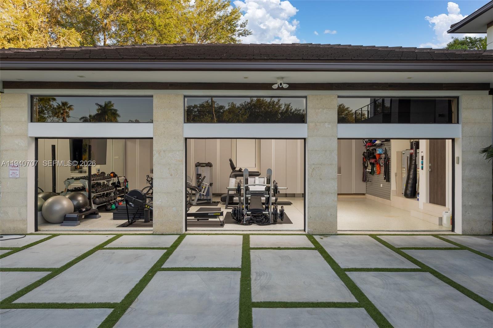 A three-bay garage converted into a home gym with concrete pavers and grass in front — 6850 SW 73rd Ct, Miami FL 33143, MIAMI, FL