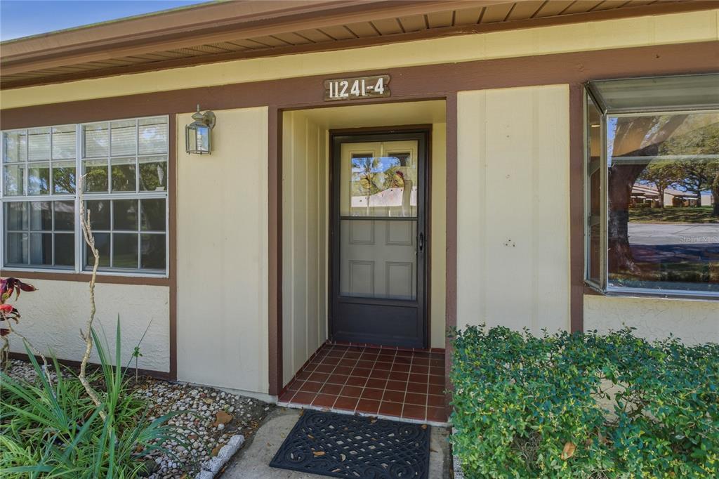 The exterior view shows a front entrance with a screen door and tiled porch — 11241 DOLLAR LAKE DRIVE UNIT 4, PORT RICHEY, FL
