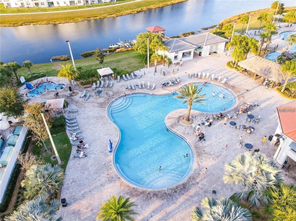An aerial view of a community swimming pool complex with lounge chairs and a lake — 2790 OXYMORON WAY, KISSIMMEE, FL