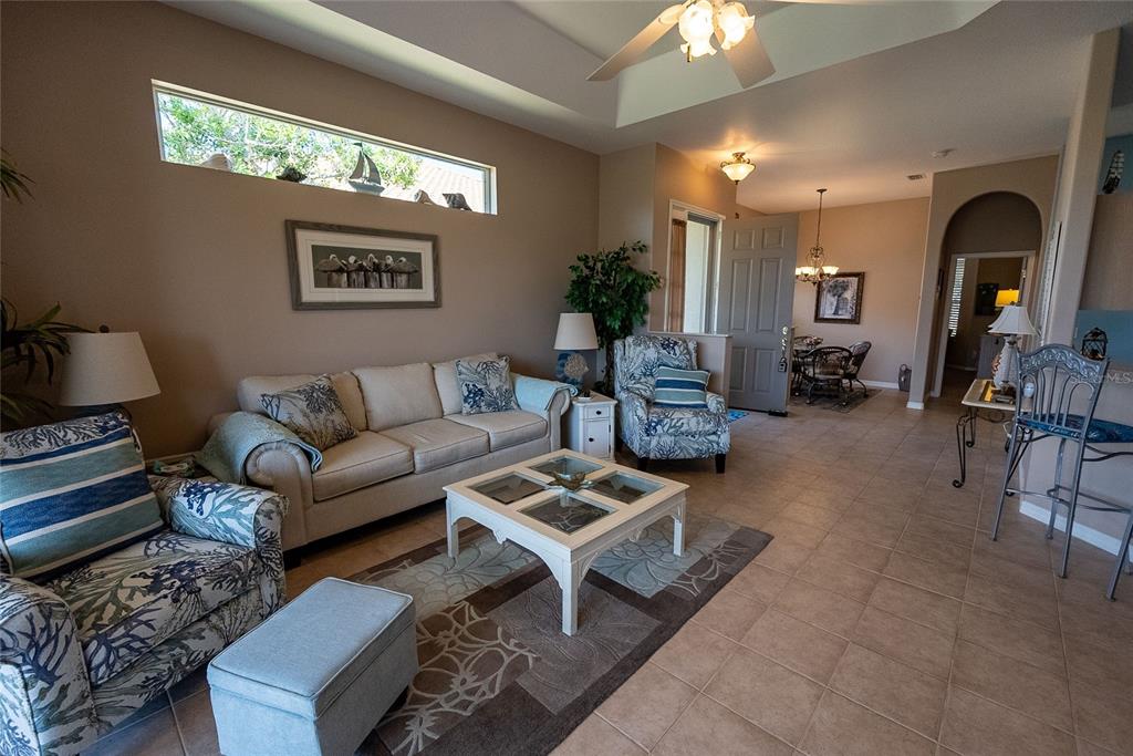 A living room with a beige sofa, patterned armchairs, a coffee table, and tile flooring — 8363 SAGO COURT, ENGLEWOOD, FL