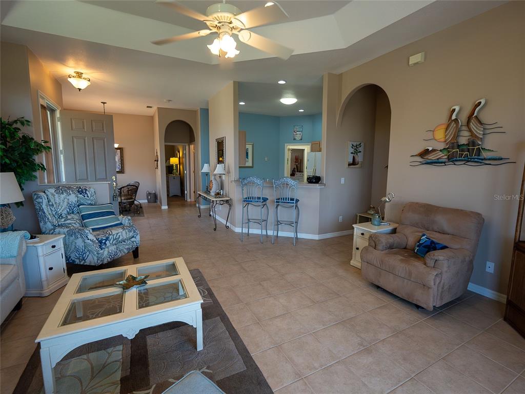 A living room with tile flooring, a ceiling fan, and a breakfast bar with stools — 8363 SAGO COURT, ENGLEWOOD, FL