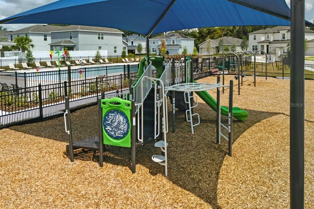 A playground with a green slide and climbing structure sits under a blue shade canopy — 1170 MAJESTY PALM CIRCLE, DELAND, FL