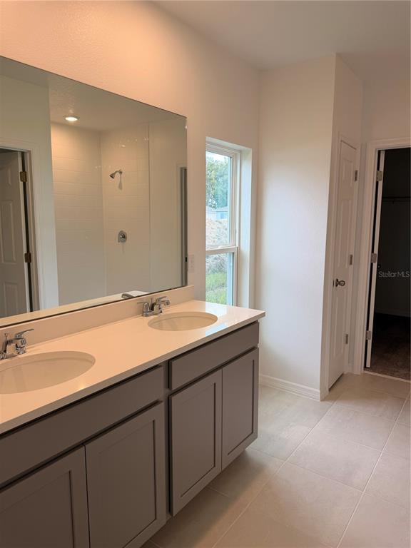 A bathroom features a double vanity with gray cabinets, white countertops, and a large mirror — 1170 MAJESTY PALM CIRCLE, DELAND, FL