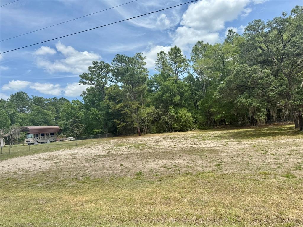 A large, cleared, sandy residential lot bordered by mature trees and a fenced-in RV — TBD SW 158TH AVE LOT 18, OCALA, FL
