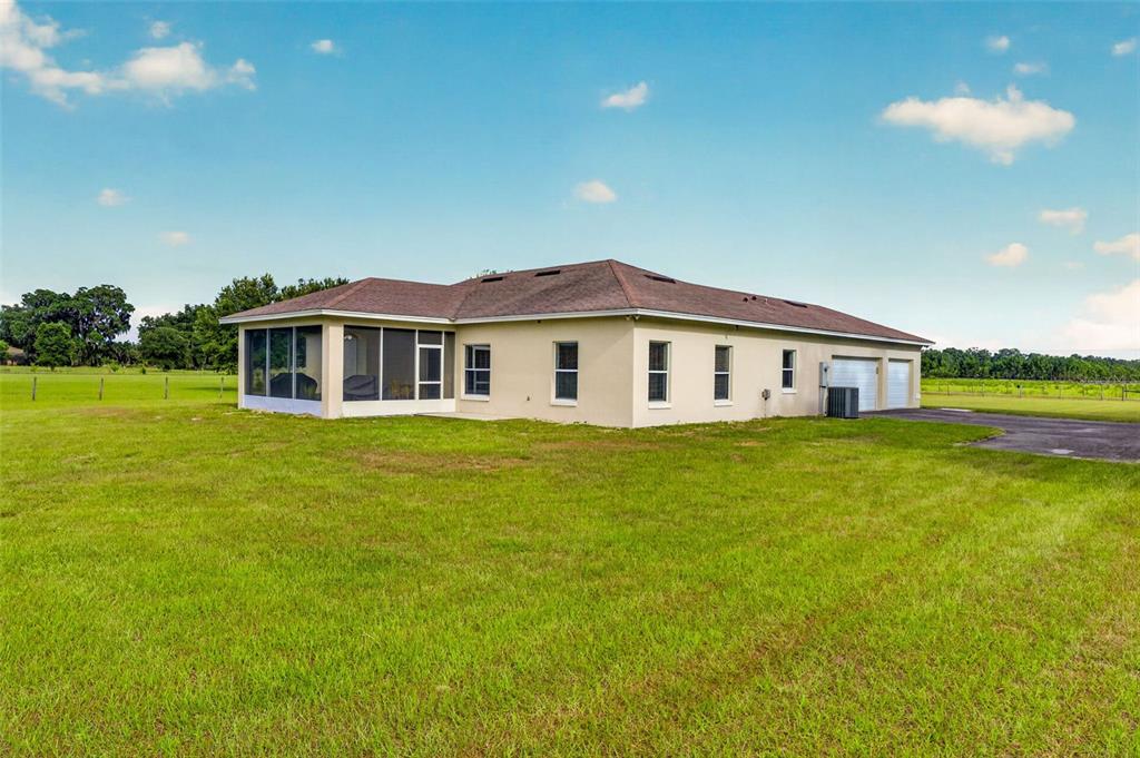 A single-story house with a screened-in porch and attached garage sits on a grassy lot — 2440 CR 546, BUSHNELL, FL