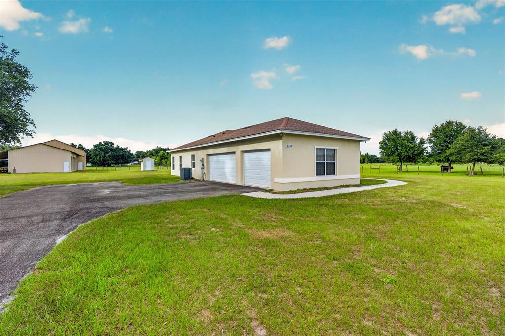 A beige detached garage with two white doors sits on a grassy rural lot — 2440 CR 546, BUSHNELL, FL