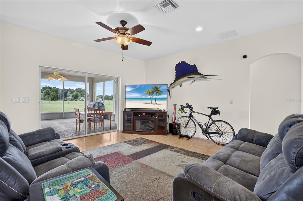 A living room features two gray sofas, a television on a stand, and a bicycle — 2440 CR 546, BUSHNELL, FL