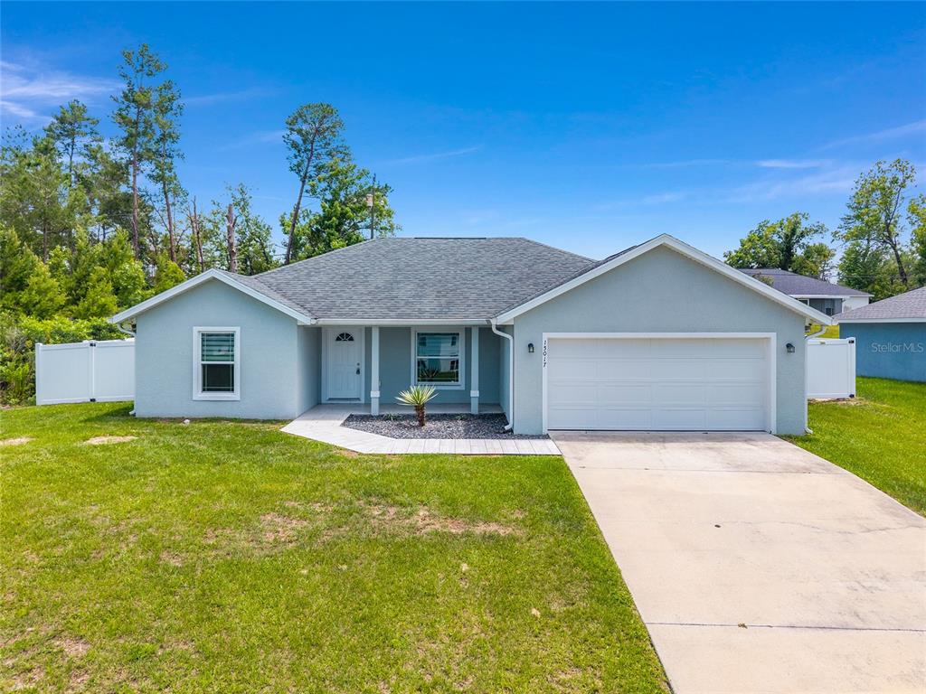 A single-story house with a light blue exterior, a two-car garage, and a concrete driveway — 15017 SW 46TH CIRCLE, OCALA, FL