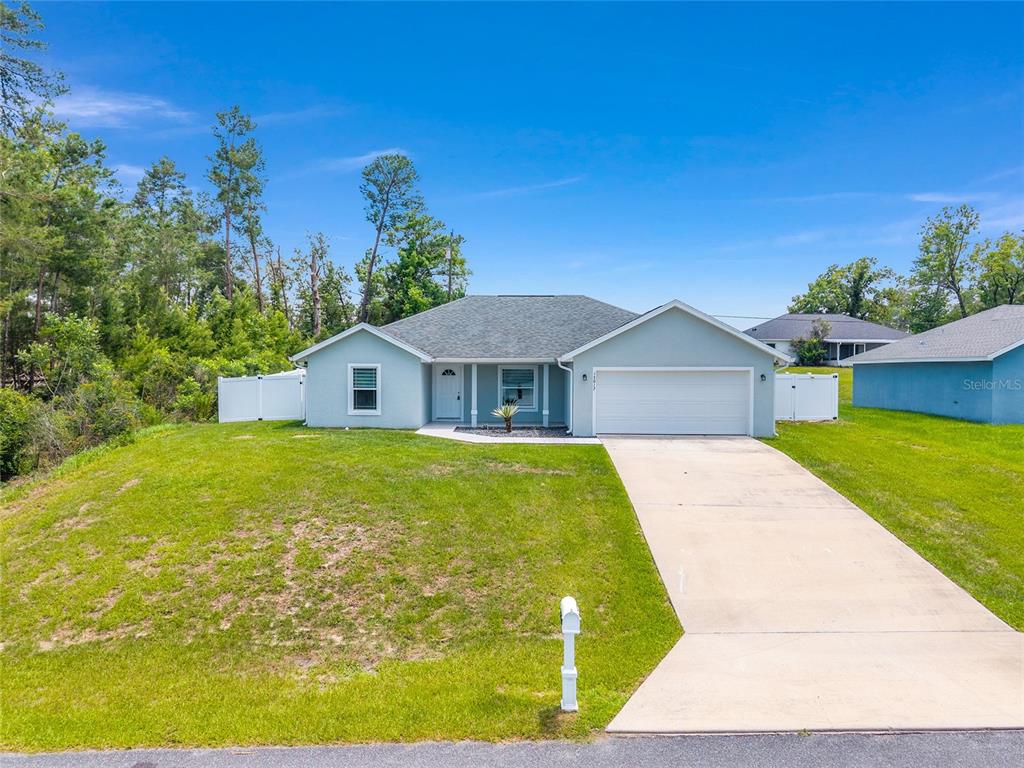 A single-story light blue house with a two-car garage and a concrete driveway — 15017 SW 46TH CIRCLE, OCALA, FL