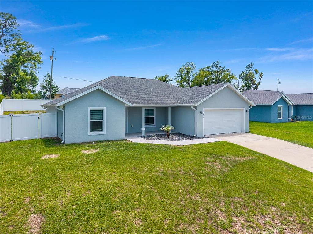 A light blue single-story house with a white garage door and a grassy front yard — 15017 SW 46TH CIRCLE, OCALA, FL