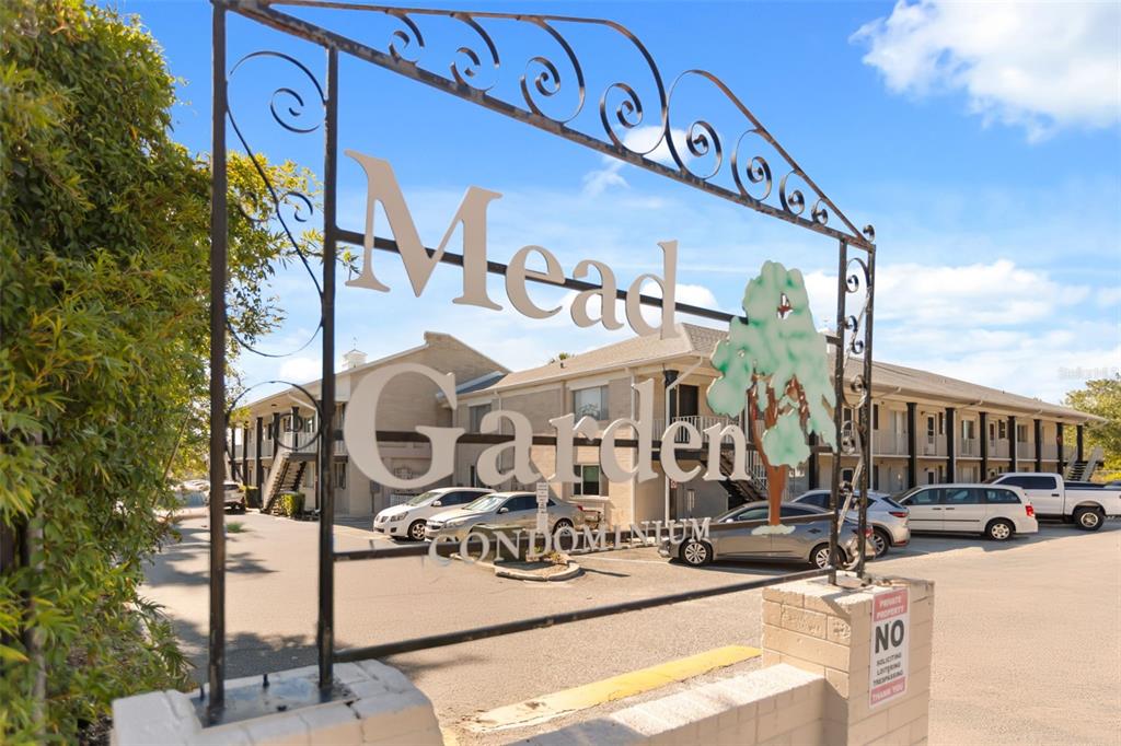 A metal sign for Mead Garden Condominium stands in front of a multi-story apartment building — 1250 S DENNING DRIVE UNIT 109, WINTER PARK, FL