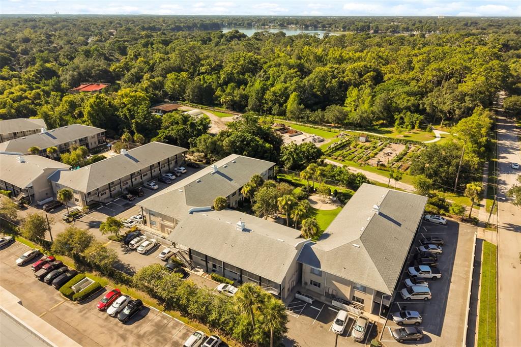 An aerial view shows multi-story apartment buildings with parking lots surrounded by trees and greenery — 1250 S DENNING DRIVE UNIT 109, WINTER PARK, FL
