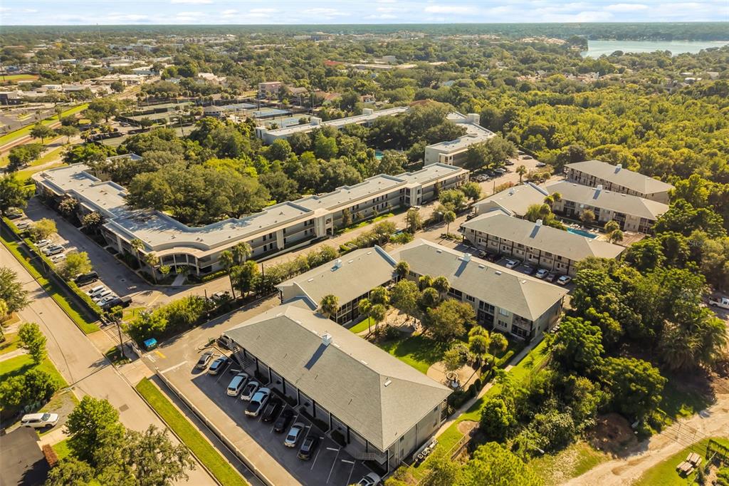 An aerial view shows multiple multi-story apartment buildings surrounded by trees and parking lots — 1250 S DENNING DRIVE UNIT 109, WINTER PARK, FL