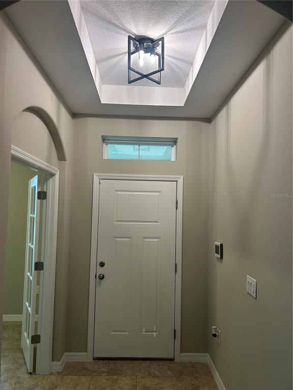 An entryway features a white front door, a transom window, and a geometric ceiling light — 720 E VICTORIA TRAILS BOULEVARD, DELAND, FL