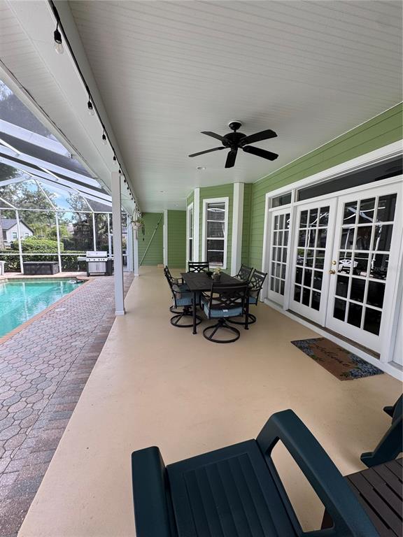 A covered patio features a dining set, ceiling fan, and pool view next to a house — 2928 CHELSEA WOODS DRIVE, VALRICO, FL