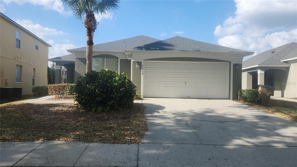 A single-story house with a two-car garage, a palm tree, and a front yard — 2618 EMERALD ISLAND BOULEVARD, KISSIMMEE, FL