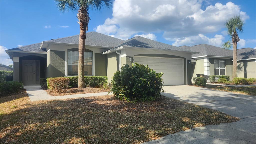 A single-story house with a two-car garage, palm trees, and a landscaped front yard — 2618 EMERALD ISLAND BOULEVARD, KISSIMMEE, FL