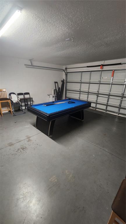 A garage converted into a game room features a blue pool table and concrete flooring — 2618 EMERALD ISLAND BOULEVARD, KISSIMMEE, FL