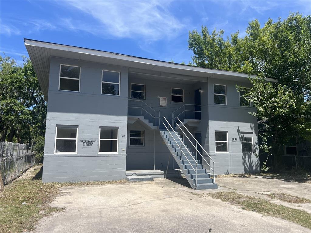 A two-story gray apartment building features an exterior staircase and a concrete parking area — 543 DIVISION STREET UNIT 1, DAYTONA BEACH, FL