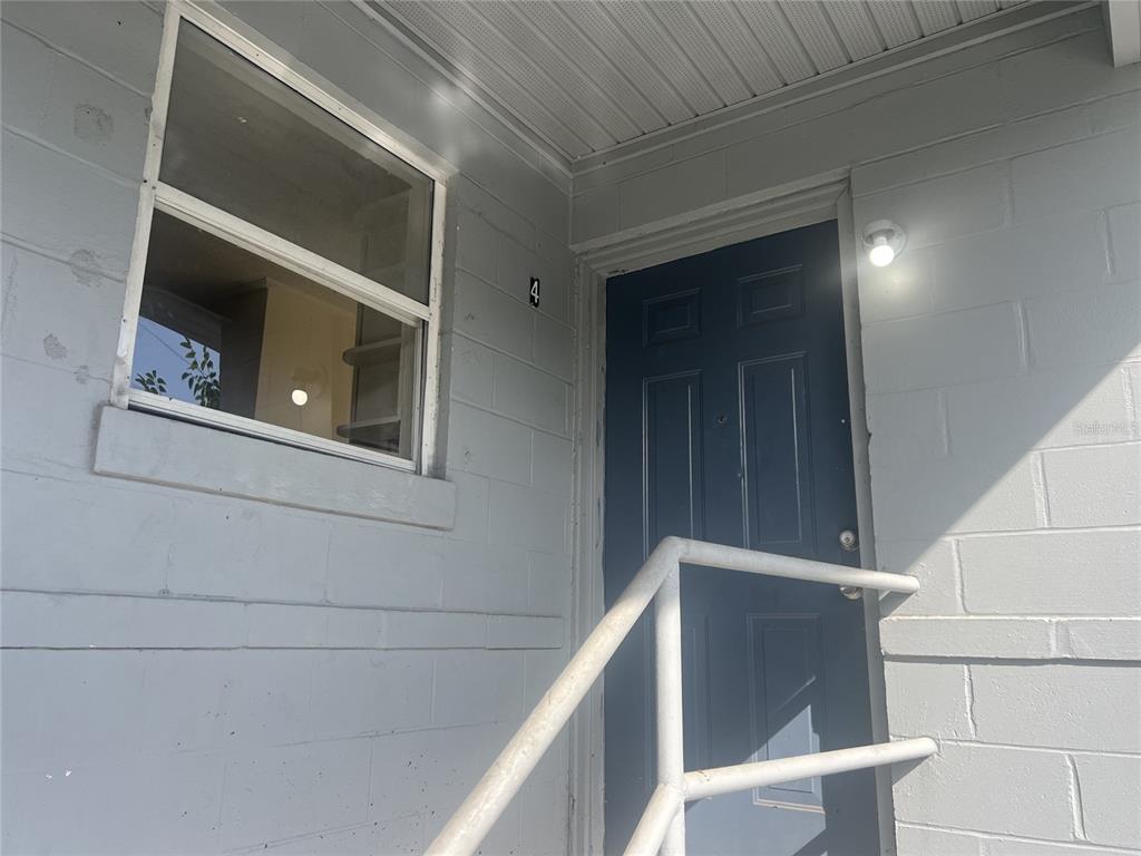 A gray concrete block exterior wall features a dark blue door labeled number four — 543 DIVISION STREET UNIT 1, DAYTONA BEACH, FL