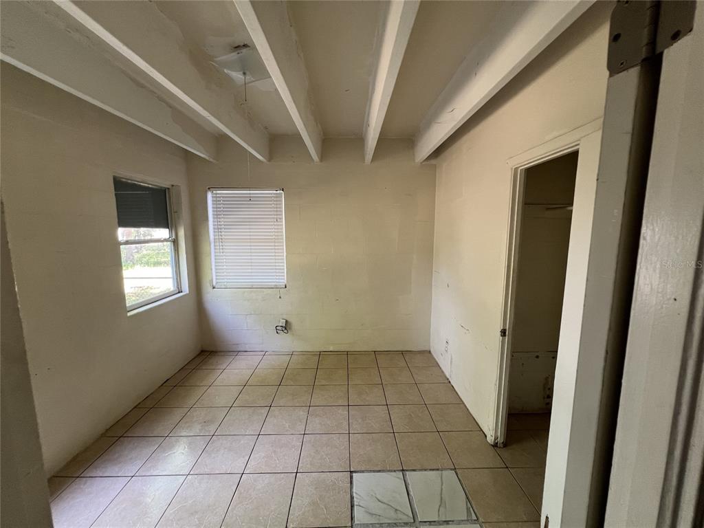 An empty room with tile flooring, exposed ceiling beams, and two windows — 543 DIVISION STREET UNIT 1, DAYTONA BEACH, FL