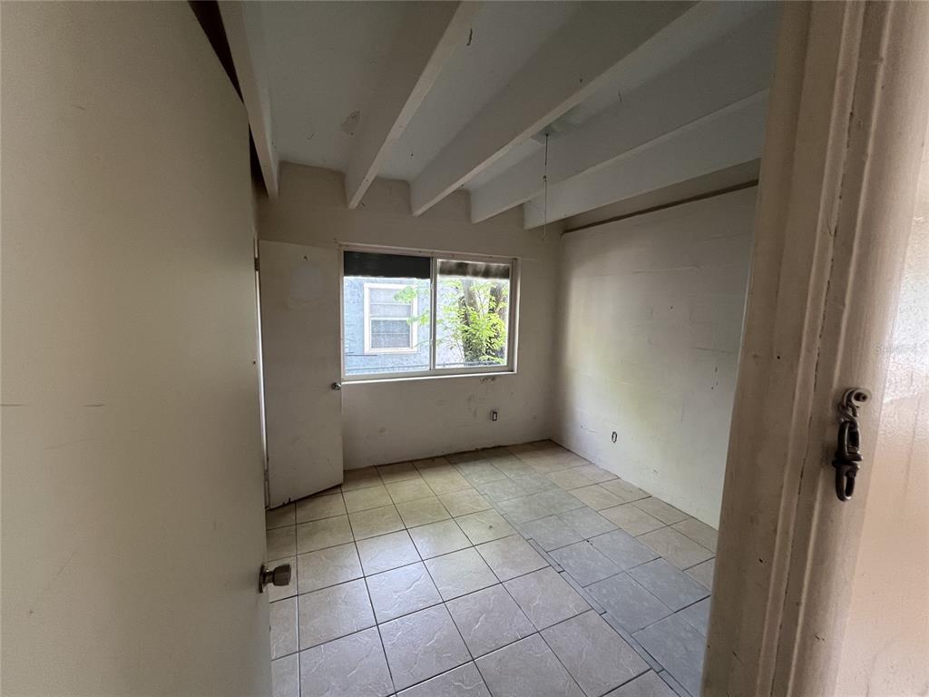 A small room with white walls, tiled flooring, and exposed ceiling beams — 543 DIVISION STREET UNIT 1, DAYTONA BEACH, FL