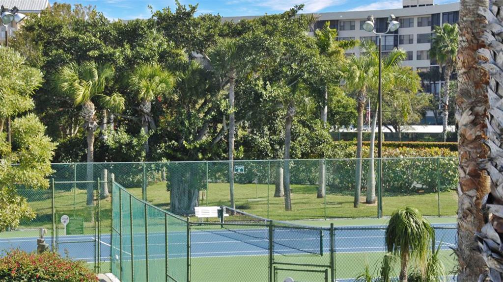 A tennis court is surrounded by a chain-link fence, palm trees, and a residential building — 1200 SIESTA BAYSIDE DRIVE UNIT 1200-G, SARASOTA, FL