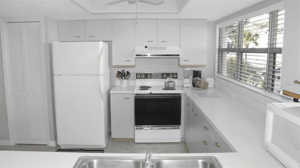 A kitchen features white cabinets, a white refrigerator, a stove, and a window with blinds — 1200 SIESTA BAYSIDE DRIVE UNIT 1200-G, SARASOTA, FL