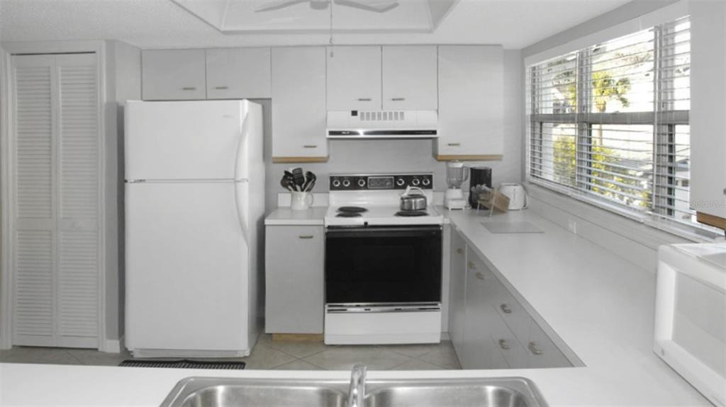 A kitchen features white cabinets, white appliances, a double sink, and a window with blinds — 1200 SIESTA BAYSIDE DRIVE UNIT 1200-G, SARASOTA, FL