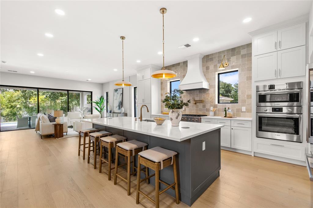 A modern kitchen features a large dark gray island, white cabinetry, and light wood flooring — 2925 OBERLIN AVENUE, ORLANDO, FL