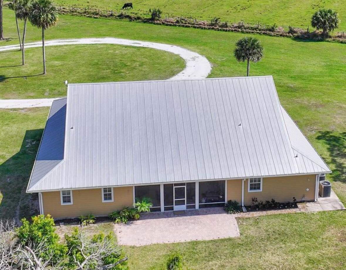 An aerial view of a tan house with a metal roof and a brick patio — 6045 21st Street SW, Vero Beach FL 32968, VERO BEACH, FL