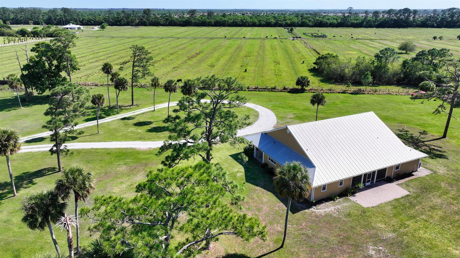 An aerial view shows a house with a metal roof surrounded by trees and pasture — 6045 21st Street SW, Vero Beach FL 32968, VERO BEACH, FL