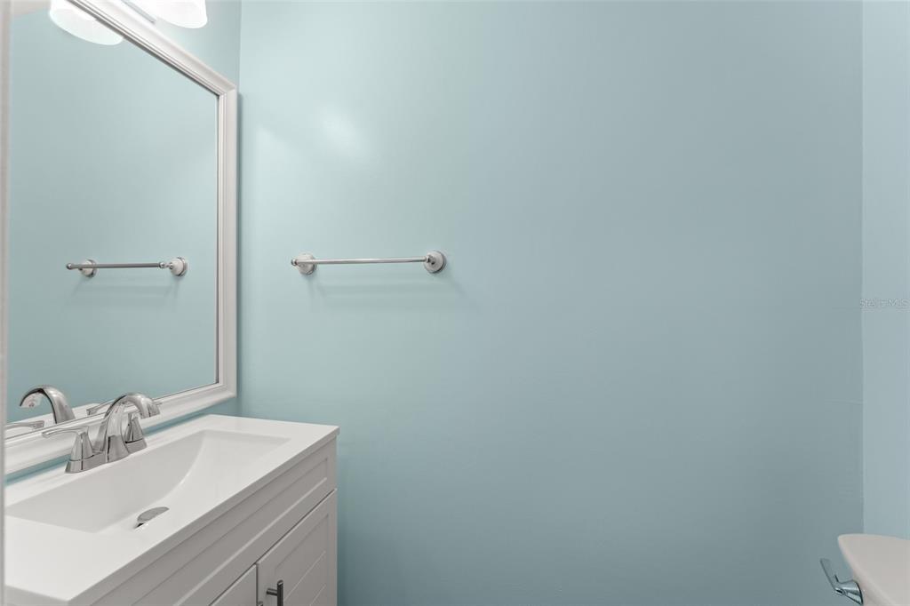 A bathroom features a white vanity, a large mirror, and light blue walls — 1220 VILLA LANE UNIT 135, APOPKA, FL