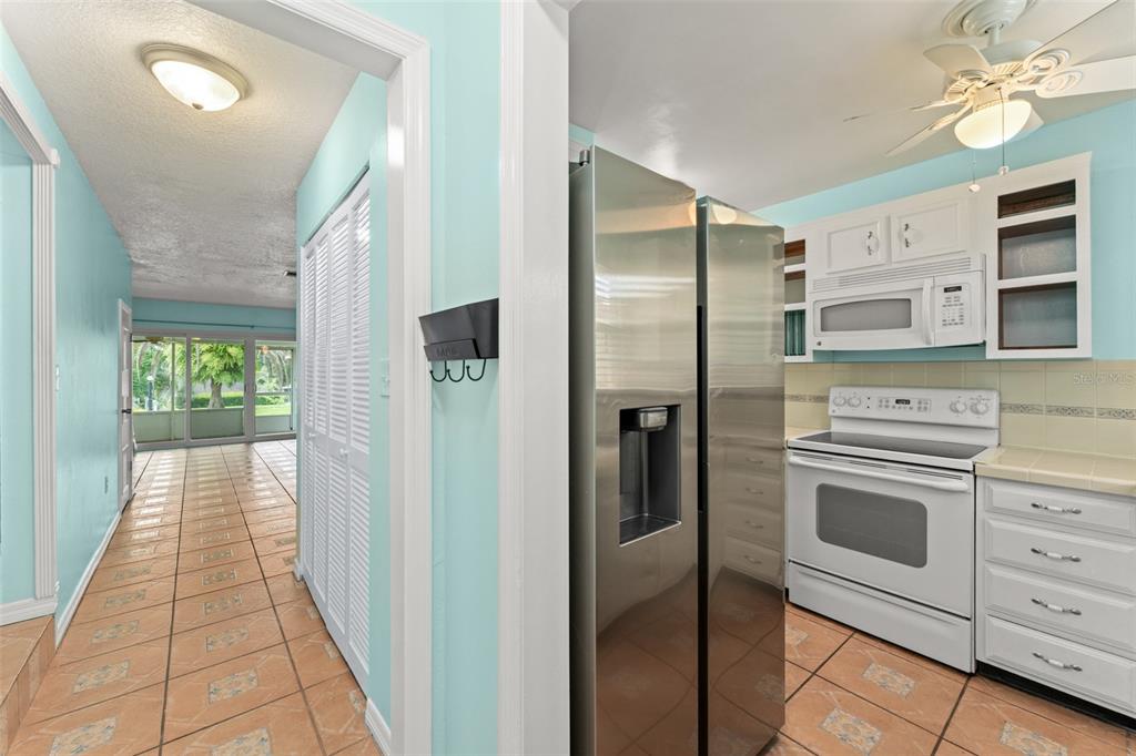 A kitchen with white cabinets and stainless steel appliances opens to a tiled hallway — 1220 VILLA LANE UNIT 135, APOPKA, FL