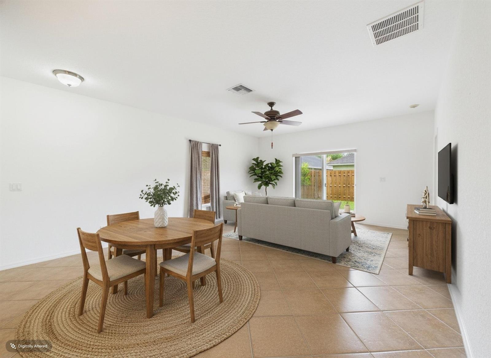 An open-concept living and dining area features tile flooring, a ceiling fan, and sliding doors — 157 Blue Grotto Drive, Fort Pierce FL 34945, FORT PIERCE, FL